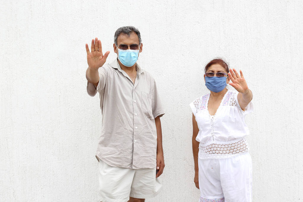ältere Latino-Paar mit schützenden Gesichtsmasken auf weißem Wandhintergrund, neue normale covid-19 - Foto, Bild