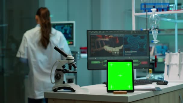 Wissenschaftlerteam arbeitet im Hintergrund mit Tablet mit grünem Bildschirm - Filmmaterial, Video