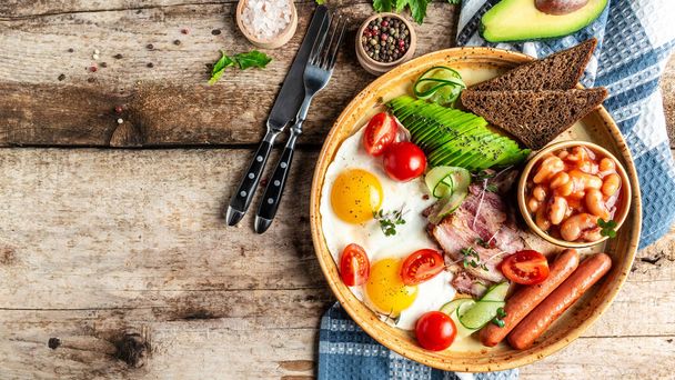 full english breakfast beans, fried eggs sunny side up, bacon slices, sausages, tomatoes, avocado on white plate. catering, banner, menu, recipe, place for text. - Photo, Image