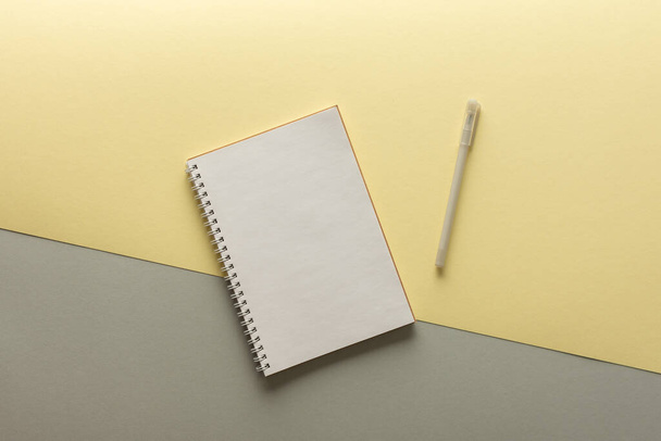 Otwarty notatnik spiralny na szarym i żółtym tle, notatnik i długopis leżą na papierze teksturalnym, płaska koncepcja układania w modnych kolorach roku żółty i szary - Zdjęcie, obraz