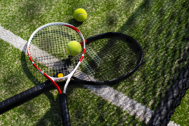 Тенісна ракетка і новий тенісний м'яч на свіжому тенісному корті
 - Фото, зображення