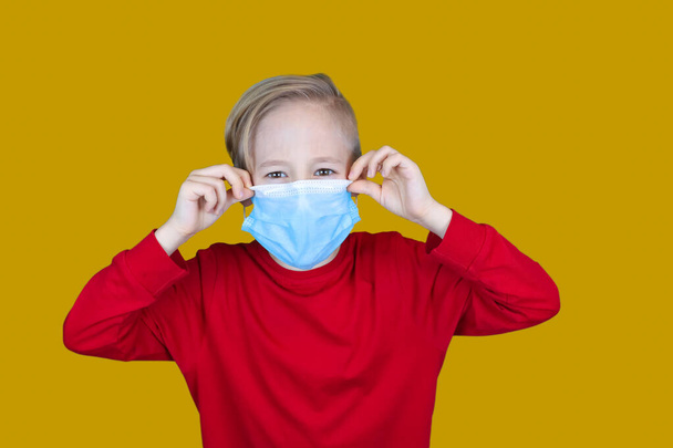 a criança usa uma máscara médica em um fundo amarelo - Foto, Imagem
