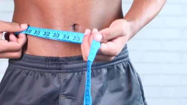 young man measuring his waist with a tape measure, close up. - Footage, Video