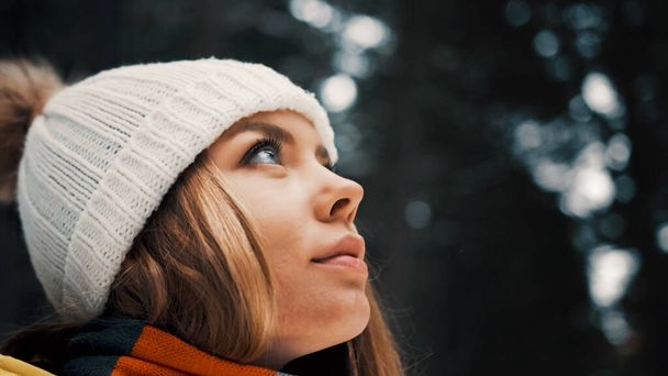 Girl with a white hat in the forest with a backpack in winter. Side view. Close up - Фото, изображение