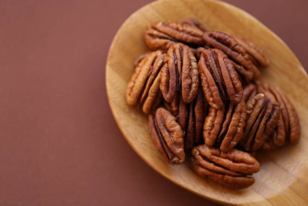 Pecan nut close-up en cuchara sobre fondo marrón.Grasas saludables.Montón de cáscara Pecans nut. Ingrediente de la dieta keto. Sabrosa comida orgánica cruda y merienda saludable  - Foto, Imagen