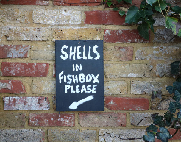 Znak instrukcja na ścianie z cegły mówi, aby zostawić muszle w skrzynce rybnej - Zdjęcie, obraz