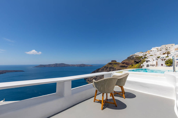 Witte architectuur op Santorini eiland, Griekenland. Ontspan over caldera uitzicht met blauwe zee, zonnige blauwe lucht. Luxe zomer reis vakantie, vakantie. Stoelen voor koppels, romantiek, liefde, huwelijksreis bestemming - Foto, afbeelding