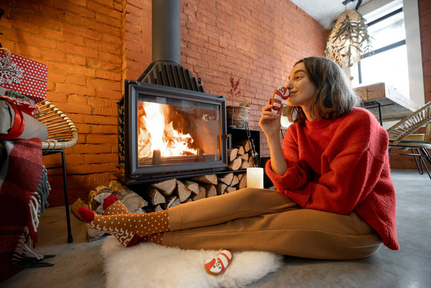 Mujer con caramelos junto a la chimenea durante unas vacaciones de invierno - Foto, imagen