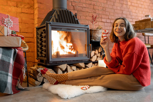 Woman with candy by the fireplace during a winter holidays - Fotografie, Obrázek
