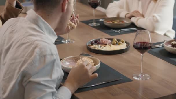 Compagnia di amici che cenano in un ristorante moderno mangiando pasti deliziosi e chiacchierando - Filmati, video