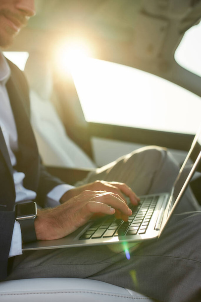 Businessman using laptop for work in car - Фото, изображение