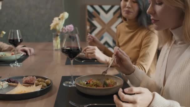 Slow-motion detailní záběr na mladé pěkné multietnické ženy, které večeří v moderní restauraci, mluví a jí krásná jídla - Záběry, video