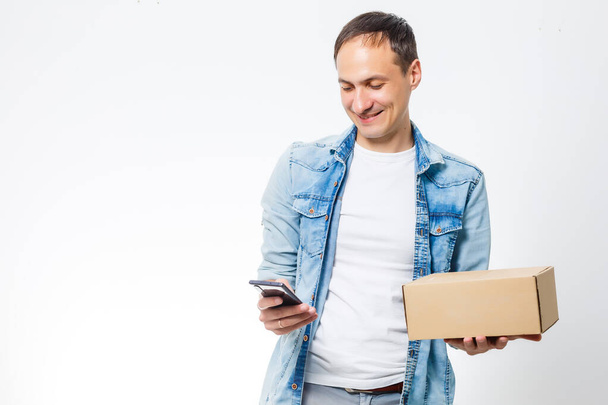 Smiling delivery man giving cardbox on white background - Photo, Image