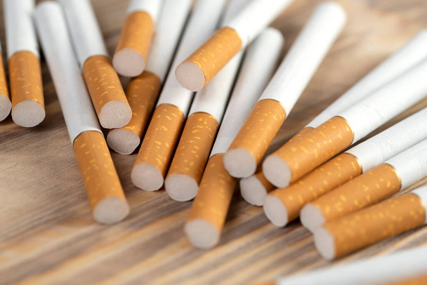 many cigarettes on a wooden background, cigarettes close up. - Photo, image