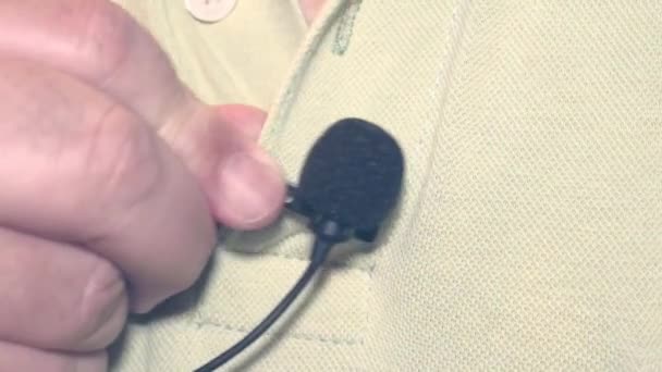 Man putting on a lavalier or tie microphone on a polo shirt. - Footage, Video