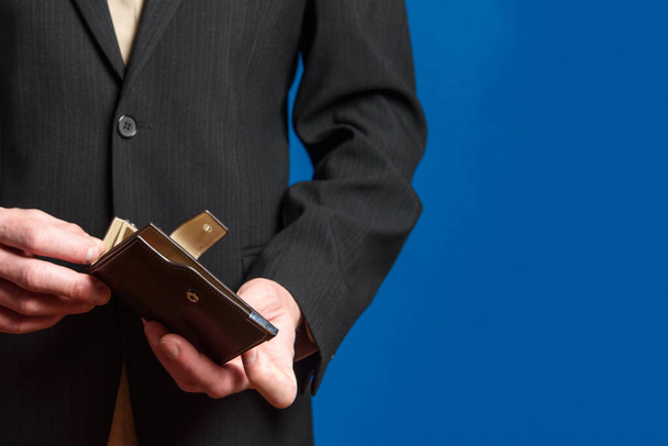 A man in a suit holds a wallet. Mens hands take out or put a bill in a wallet. - Foto, imagen