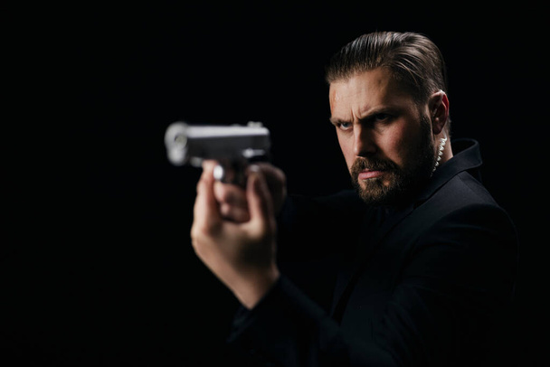 Serious man aiming with gun over black background - Foto, Imagem