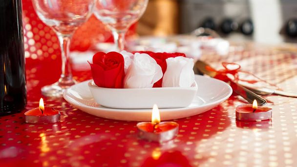 Valentines day. Bottle of vine, glasses, red roses, candles - red background - Foto, Imagen