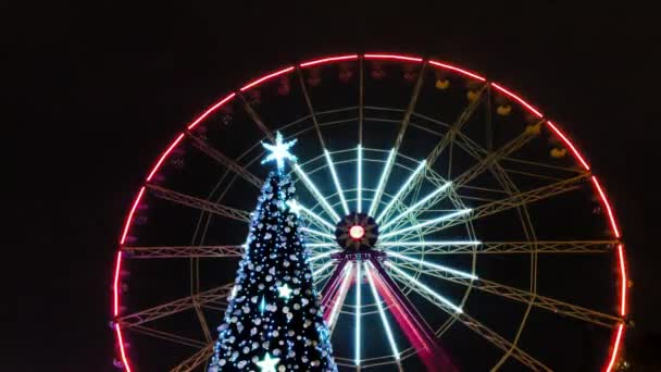 Otáčení ruského kola a vánoční Nový rok strom zblízka pohled v Charkově centru parku v noci barevné jasné osvětlení. Sezónní sváteční dekorace - Záběry, video