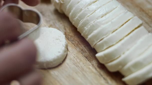 Ahşap kesme tahtasının üzerinde kalp şeklinde mozzarella peyniri kesen kadın elleri. Sevgililer Günü için yemek hazırlıyorum. 4k video - Video, Çekim