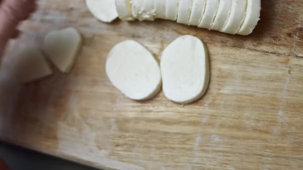 Ahşap kesme tahtasının üzerinde kalp şeklinde mozzarella peyniri kesen kadın elleri. Sevgililer Günü için yemek hazırlıyorum. 4k video, üst görünüm - Video, Çekim