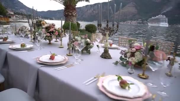 Pöytä hääjuhlissa, koristeltu kukilla, kynttilänjaloilla ja nuorilla granaattiomenoilla Kotorin laiturilla. - Materiaali, video