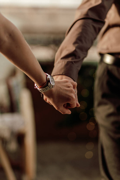 Χέρια του ρομαντικού ζευγαριού περπάτημα ευτυχισμένοι μαζί σε εσωτερικούς χώρους στο διαμέρισμα. Κοντινό πλάνο κρατώντας τα χέρια μαζί - Φωτογραφία, εικόνα