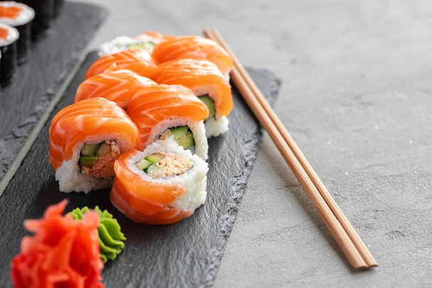 Sushi roll covered with fresh salmon served on plate - 写真・画像