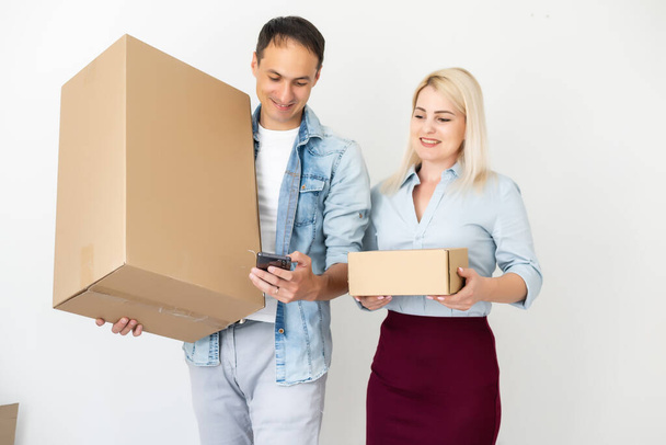 people, delivery, shipping and postal service concept - happy couple opening cardboard box or parcel at home - Foto, Imagen
