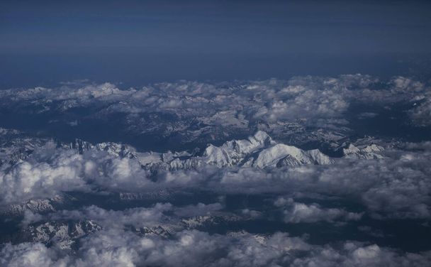 Alpine sneeuw bedekte bergtoppen top natuur panorama landschap met wolken uit vliegtuig over Alpen Europa - Foto, afbeelding