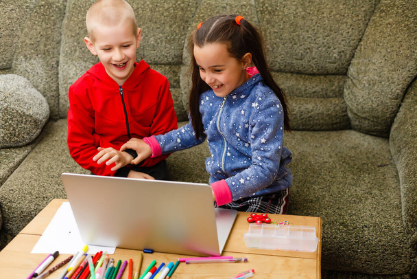 Twee mooie leuke gelukkig lachende kinderen, een jongen en een meisje, gebruik laptop voor afstandsonderwijs of entertainment. - Foto, afbeelding