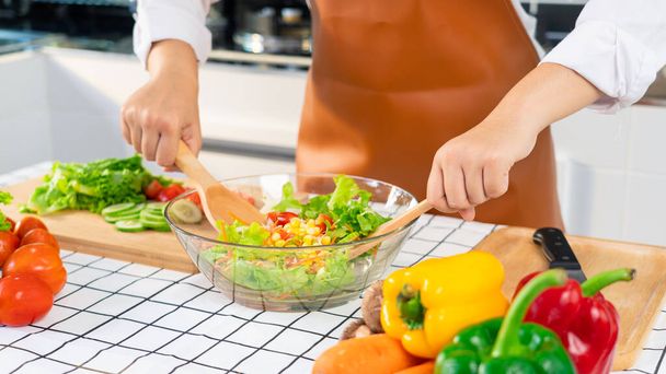 woman in the process of preparing healthy food Vegetable Salad mixing salad wooden spoon in kitchen at home Dieting Concept. - Foto, Bild