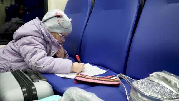 Cute Little Girl rysować obraz przez marker Pen w pociągu w podróży - Materiał filmowy, wideo