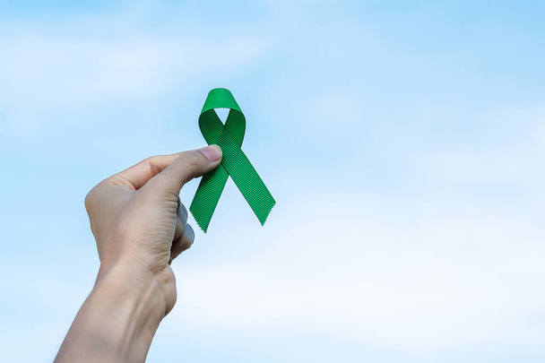 Woman holding green Ribbon for supporting people living and illness. Liver, Gallbladders bile duct, kidney Cancer and Lymphoma Awareness month concept - Foto, imagen