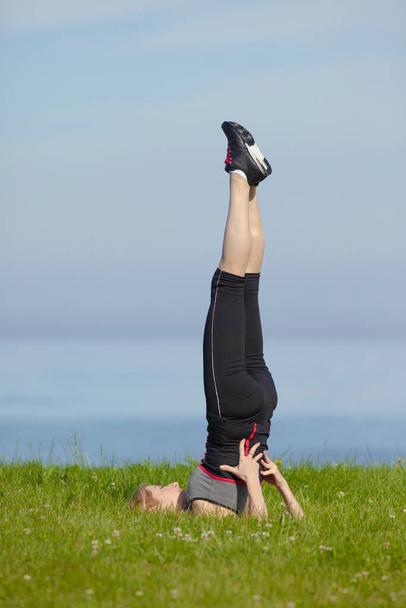 Yoga femme en vêtements de sport relaxant par la mer - Photo, image