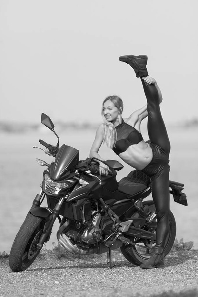 海を背景にスポーツバイクを持つ若い女性は - 写真・画像