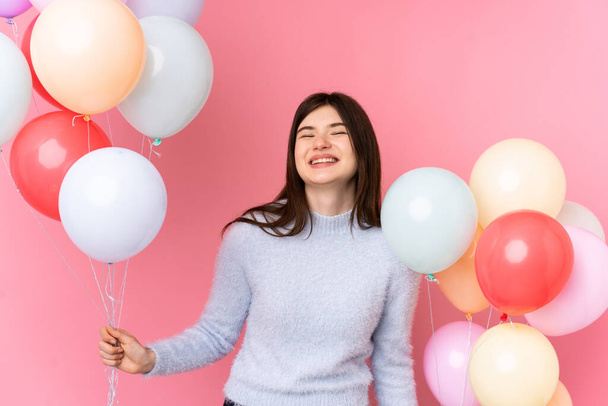 Young Ukrainian teenager girl holding lots of balloons over isolated pink background - Φωτογραφία, εικόνα