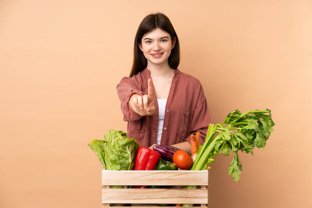 Jungbäuerin mit frisch gepflücktem Gemüse in einer Kiste, die einen Finger zeigt und hebt - Foto, Bild