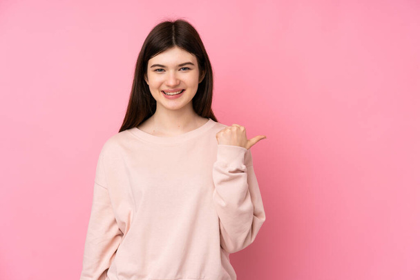 Mladý ukrajinský teenager dívka přes izolované růžové pozadí ukazuje na stranu prezentovat produkt - Fotografie, Obrázek
