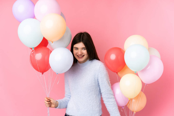 Joven adolescente ucraniano sosteniendo un montón de globos sobre fondo rosa aislado - Foto, Imagen
