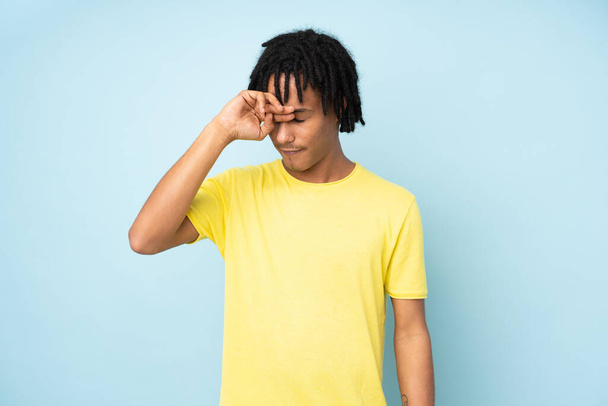 Junger Afroamerikaner isoliert auf blauem Hintergrund mit müdem und krankem Gesichtsausdruck - Foto, Bild