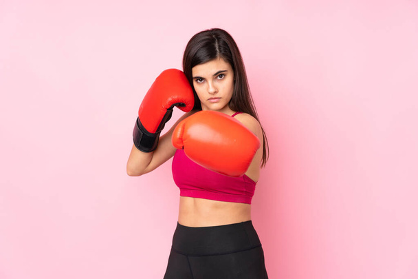 Mujer deportiva joven sobre fondo rosa aislado con guantes de boxeo - Foto, imagen