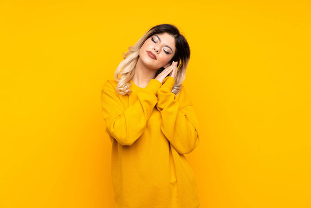 Teenager dívka izolované na žlutém pozadí dělat spánek gesto v dorable výraz - Fotografie, Obrázek