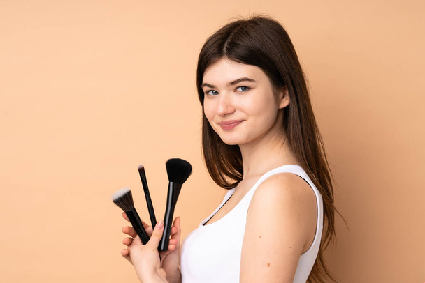 Junge ukrainische Teenager Mädchen über isolierten Hintergrund halten Make-up-Pinsel - Foto, Bild