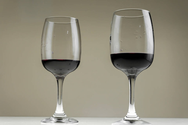 Two glasses of red wine on a blurred homogeneous background. - Foto, imagen