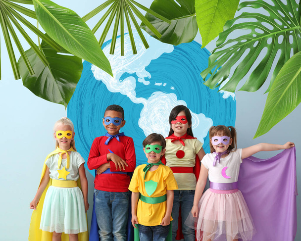 Милые маленькие дети, одетые как супергерои, рядом с рисунком планеты на цветном фоне. День Земли - Фото, изображение