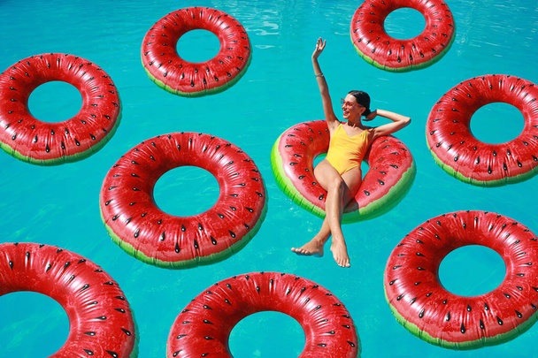 Piękna młoda kobieta z nadmuchiwanymi pierścieniami relaksująca się w basenie - Zdjęcie, obraz