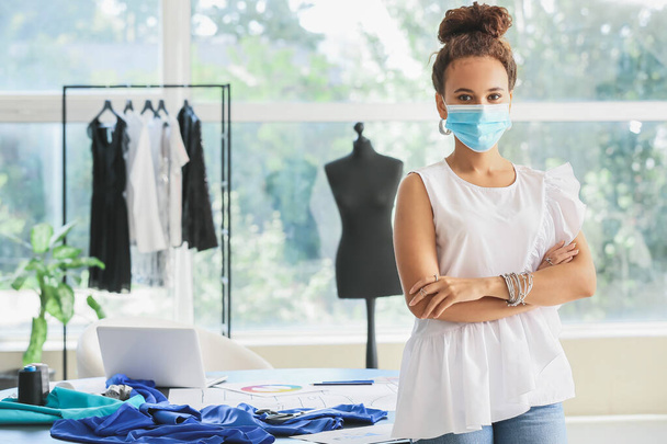 Žena módní návrhářka nosí lékařskou masku ve studiu - Fotografie, Obrázek