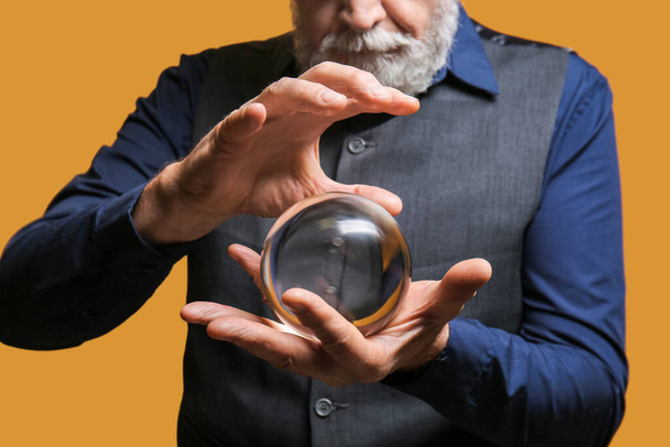 Male fortune teller with crystal ball on color background, closeup - Fotografie, Obrázek