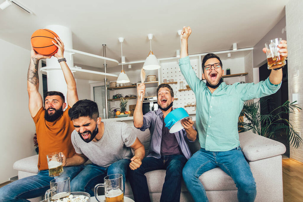 Щасливі чоловіки друзі в чорному обличчі захисна маска дивиться баскетбол вдома
 - Фото, зображення